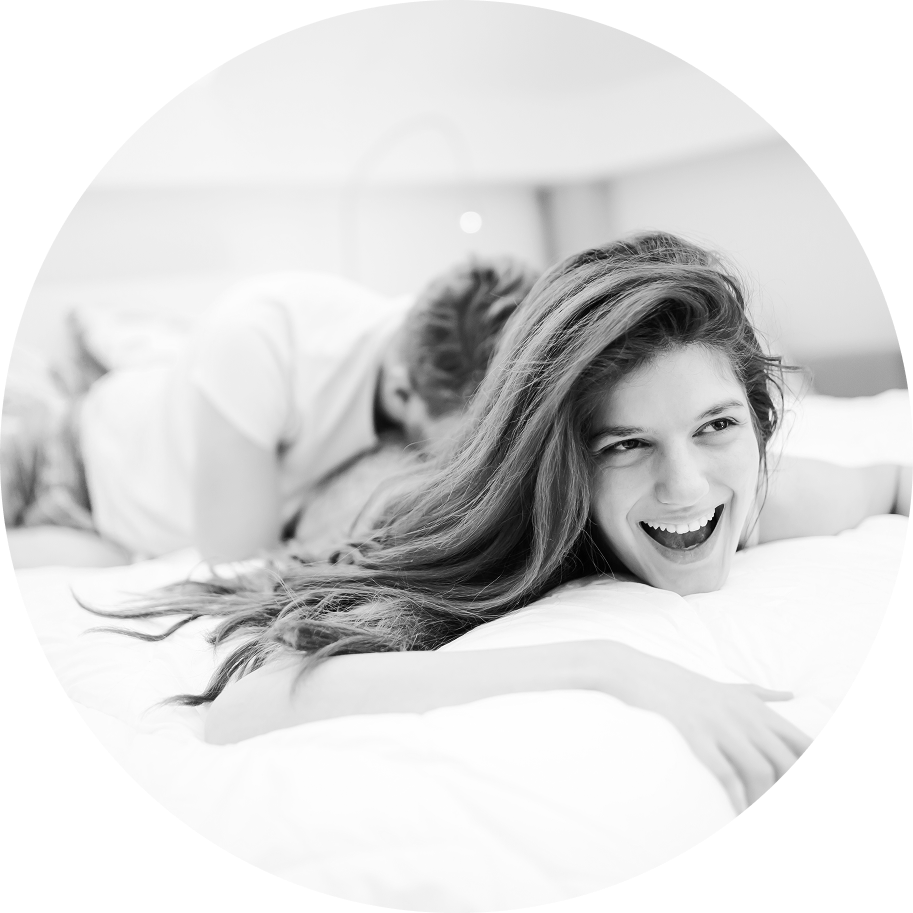 Lesbian couple lying in bed together, smiling and embracing in a cozy setting
